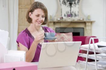 Royalty Free Photo of a Woman Drinking Coffee at Her Desk