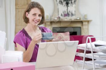 Royalty Free Photo of a Woman Drinking Coffee at Her Desk