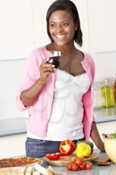 Royalty Free Photo of a Woman Enjoying Wine While Cooking Dinner