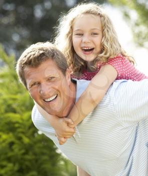Royalty Free Photo of a Father Giving His Daughter a Piggyback Ride