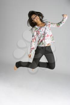 Studio Portrait Of Young Woman Jumping In Air