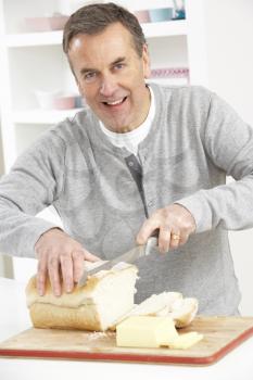 Senior Man Slicing Bread In Kitchen