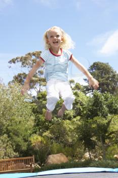 Young Girl Jumping On Trampoline In Garden