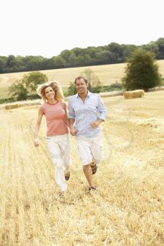 Couple Running Together Through Summer Harvested Field