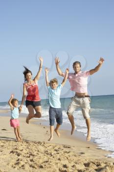 Portrait Of Family On Beach Holiday Jumping In Air