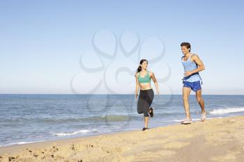 Young Couple In Fitness Clothing Running Along Beach