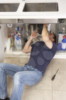 Plumber Working On Sink In Kitchen