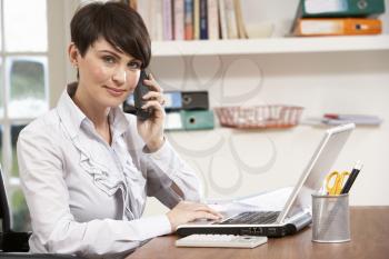 Woman Working From Home Using Laptop On Phone