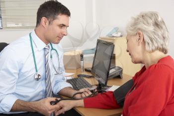 British doctor taking senior woman's blood pressure