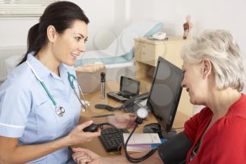 British nurse taking senior woman's blood pressure