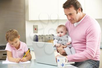 Father with children using laptop in kitchen