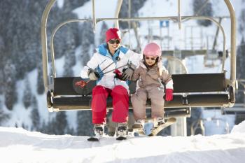 Mother And Daughter Getting Off chair Lift On Ski Holiday In Mountains