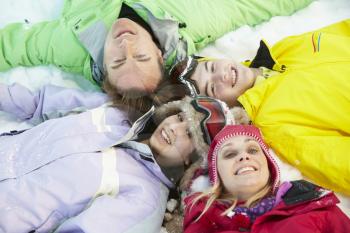 Overhead View Of Teenage Family Lying In Snow On Ski Holiday In Mountains