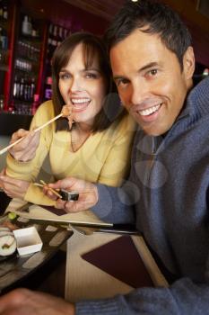 Couple Enjoying Sushi In Restaurant