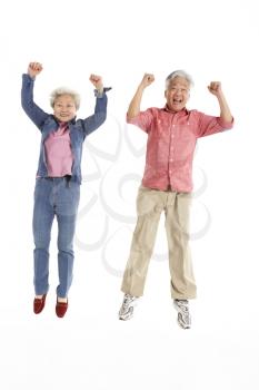 Studio Shot Of Chinese Senior Couple Jumping In Air
