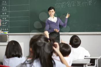 Teacher Standing By Blackboard In Chinese School Classroom