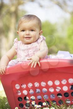 Baby Girl In Summer Dress Sitting In Laundry Basket