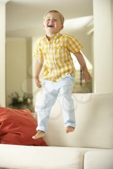 Young Boy Jumping On Sofa At Home
