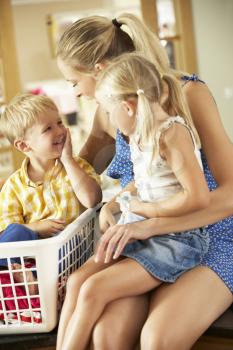Mother And Children Sorting Laundry Sitting On Kitchen Counter