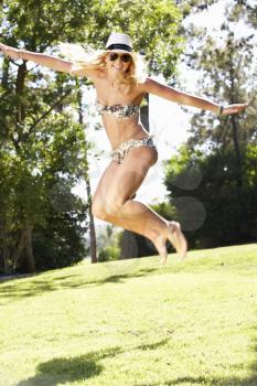 Woman Wearing Bikini Jumping In Garden