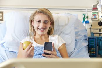 Teenage Female Patient Using Mobile Phone In Hospital Bed