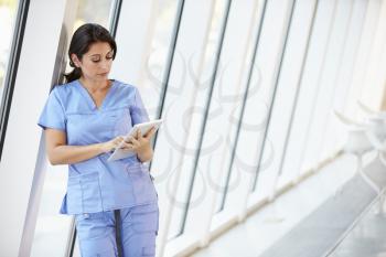 Nurse Using Digital Tablet In Corridor Of Modern Hospital
