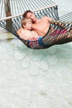 Father And Son Relaxing In Beach Hammock