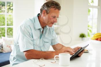 Middle Aged Man Using Digital Tablet Over Breakfast