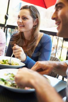 Woman Enjoying Meal At Outdoor Restaurant With Friends