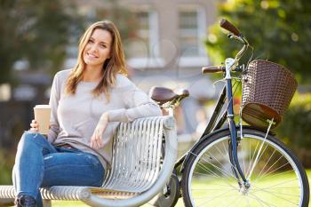 Woman Relaxing On Park Bench With Takeaway Coffee