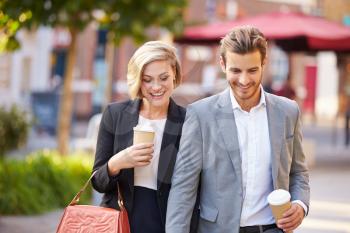 Business Couple Walking Through Park With Takeaway Coffee