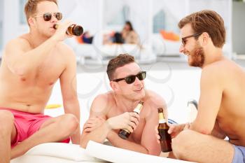 Three Young Male Friends On Holiday By Pool Together
