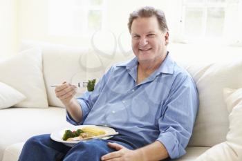 Overweight Man Eating Healthy Meal Sitting On Sofa