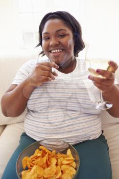 Overweight Woman At Home Eating Chips And Drinking Wine