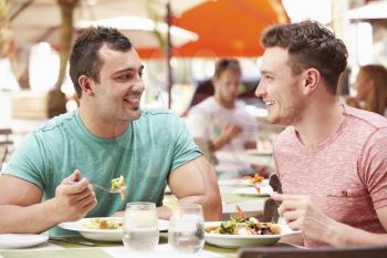 Male Couple Enjoying Lunch In Outdoor Restaurant