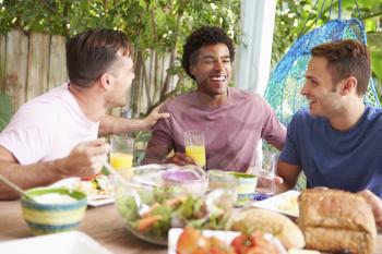 Three Male Friends Enjoying Meal Outdoors At Home