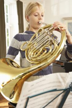 Girl playing French horn at home