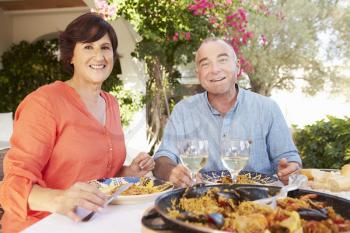 Mature Hispanic Couple Enjoying Outdoor Meal At Home