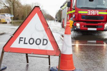 Warning Traffic Sign On Flooded Road With Fire Engine