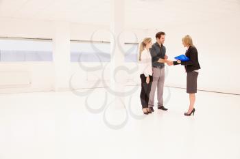 Estate Agent Shaking Hands With Clients In Empty Office