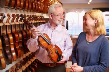 Salesman Advising Customer Buying Violin