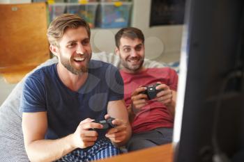 Two Male Friends In Pajamas Playing Video Game Together