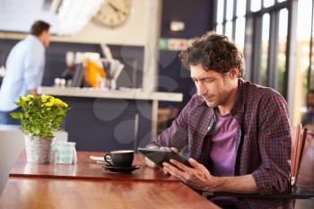Man at coffee shop, using digital tablet