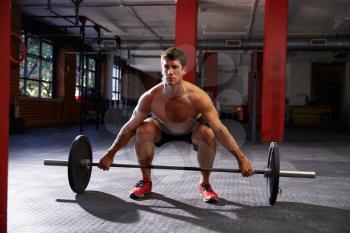 Bare Chested Man In Gym Preparing To Lift Weights