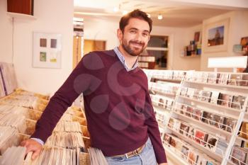 Shop owner posing in a record shop, smiling