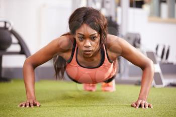 Young woman doing push ups at a gym