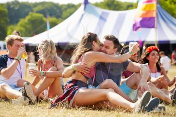 Couple sitting on the grass embracing at a music festival