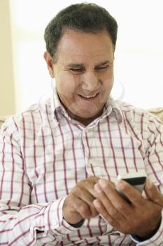Senior Hispanic Man Using Smartphone At Home