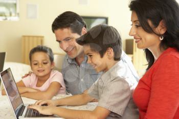 Young Hispanic Family Using Computer At Home