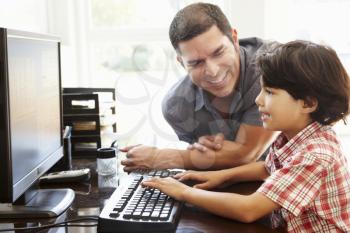 Hispanic father and son using computer at home